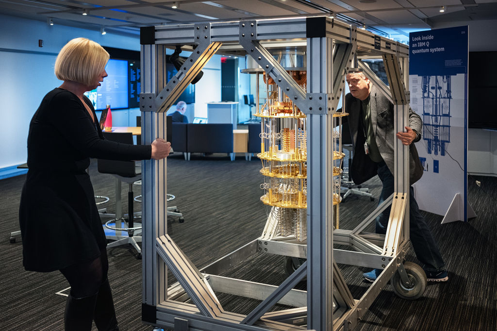 Photo of two people moving a frame carrying the internal circuitry of a quantum computer.