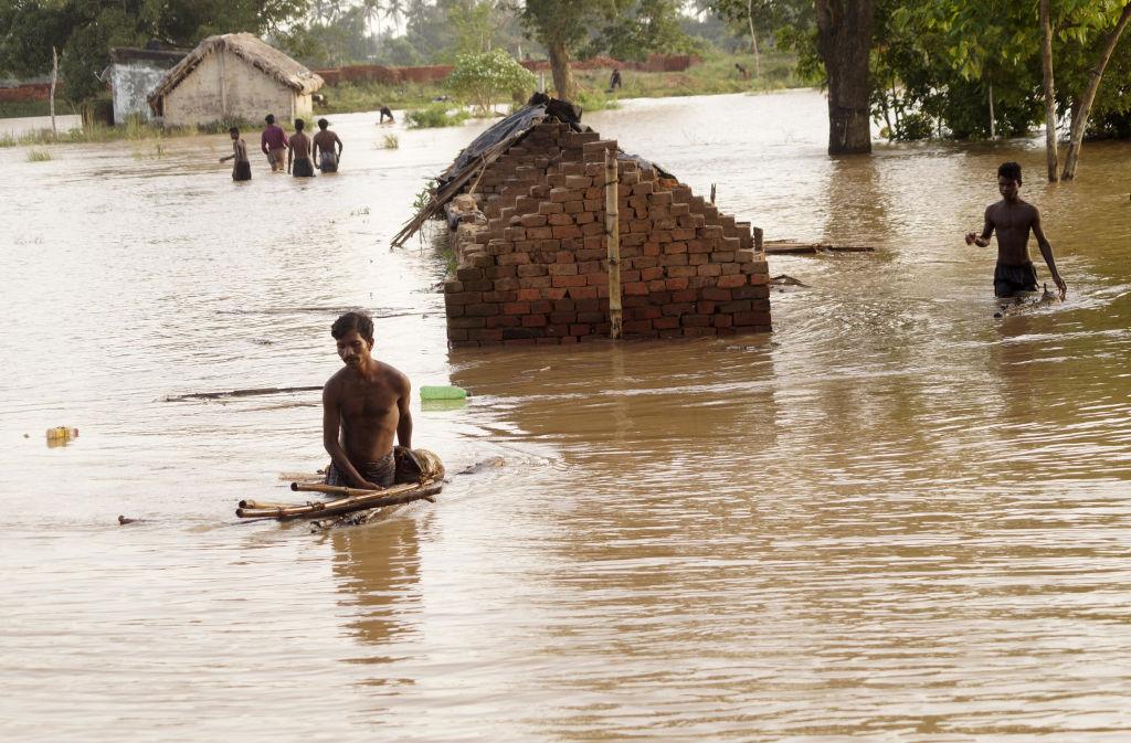 People wading through a flooded village in India.