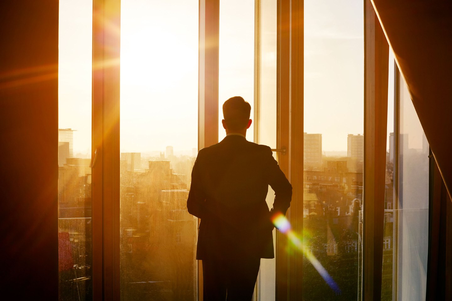man looking out window of office building