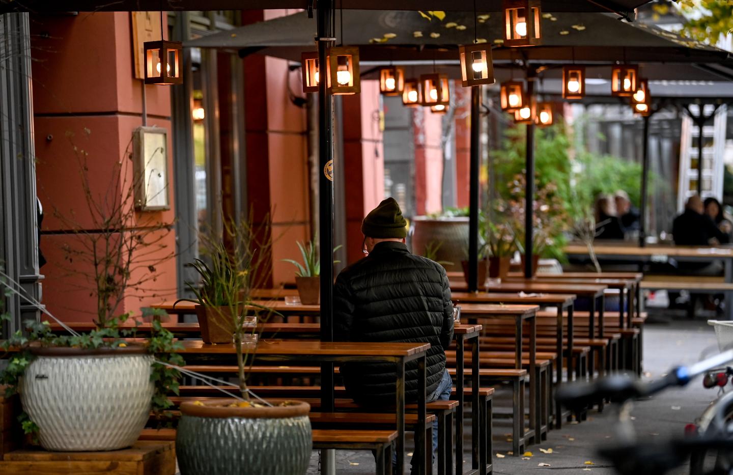 26 October 2020, Berlin: A man is sitting outside a restaurant.