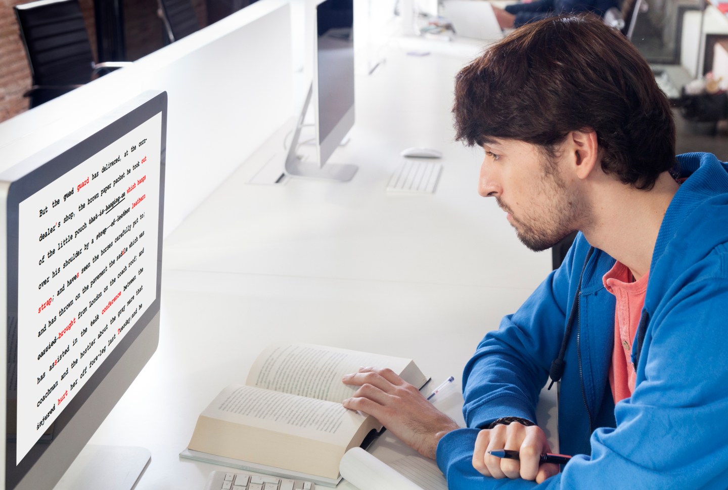 A person proofreading a text on a computer with a book open in front of them.