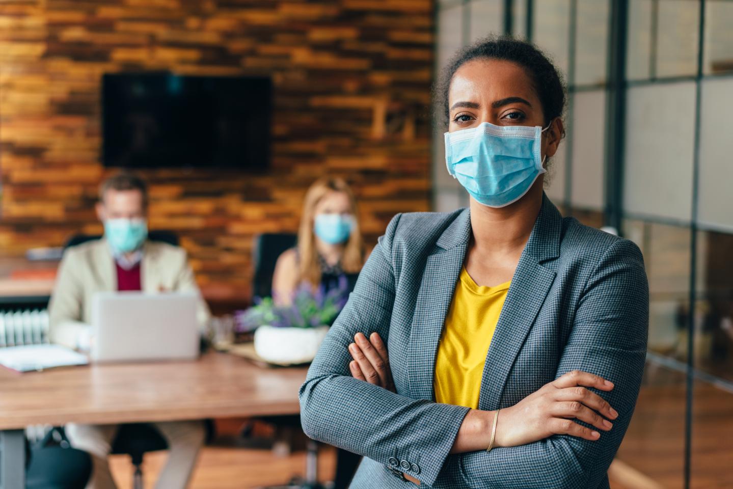 Businesspeople wearing masks in the office for safety during COVID-19 pandemic.