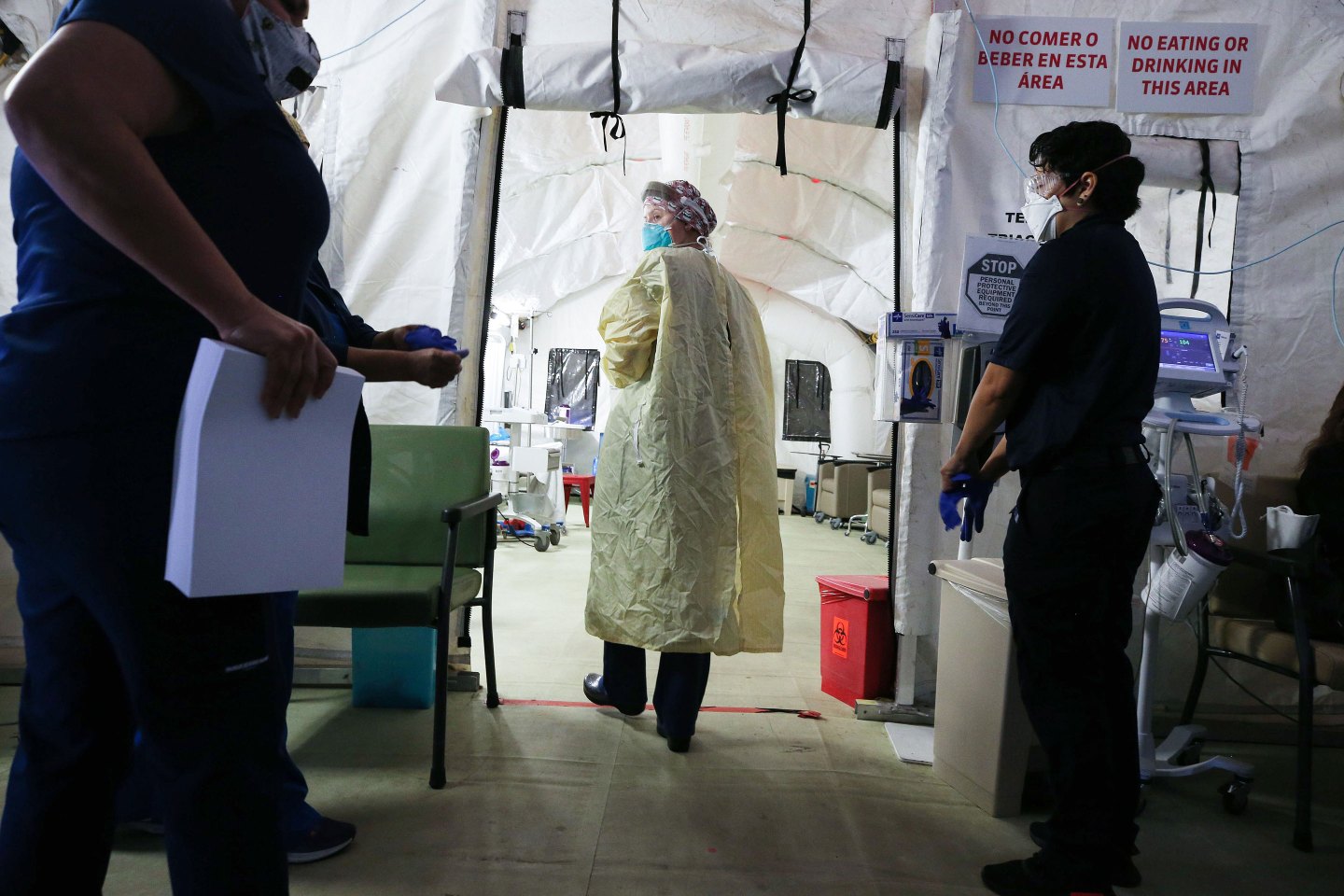 Clinicians and a paramedic work in a makeshift tent triage center for patients suspected of having COVID-19 outside El Centro Regional Medical Center in hard-hit Imperial County, Calif.