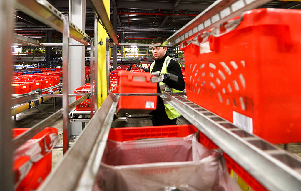 Image of an Ocado warehouse worker loading a crate inside one of the company's automated warehouses.