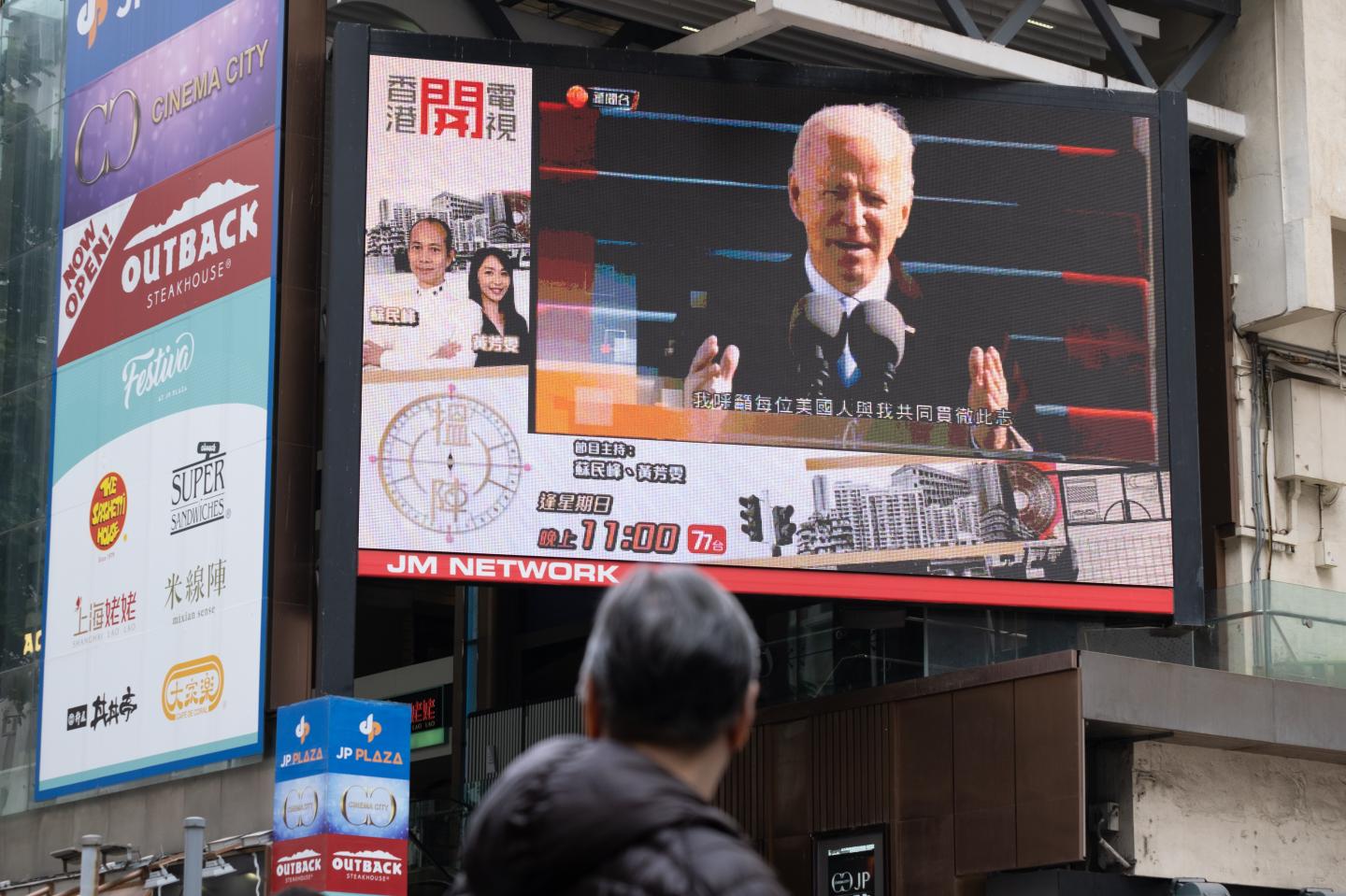 A man is seen watching the news report of the inauguration of U.S. President Joe Biden on a large screen.