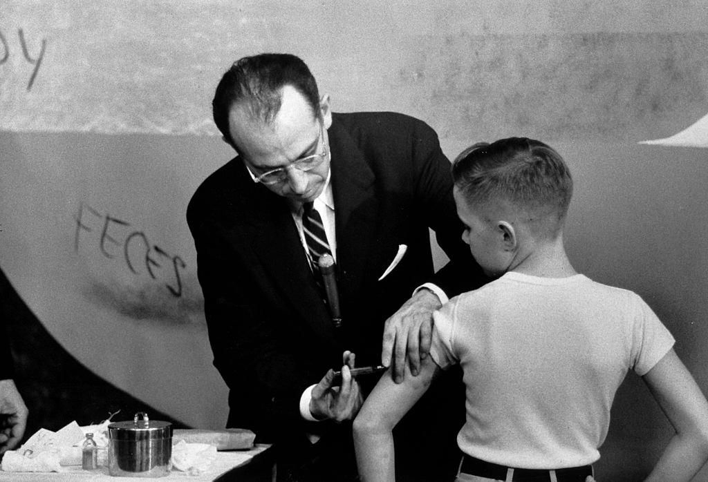 A photo of Jonas Salk injecting a boy with the polio vaccine he invented.