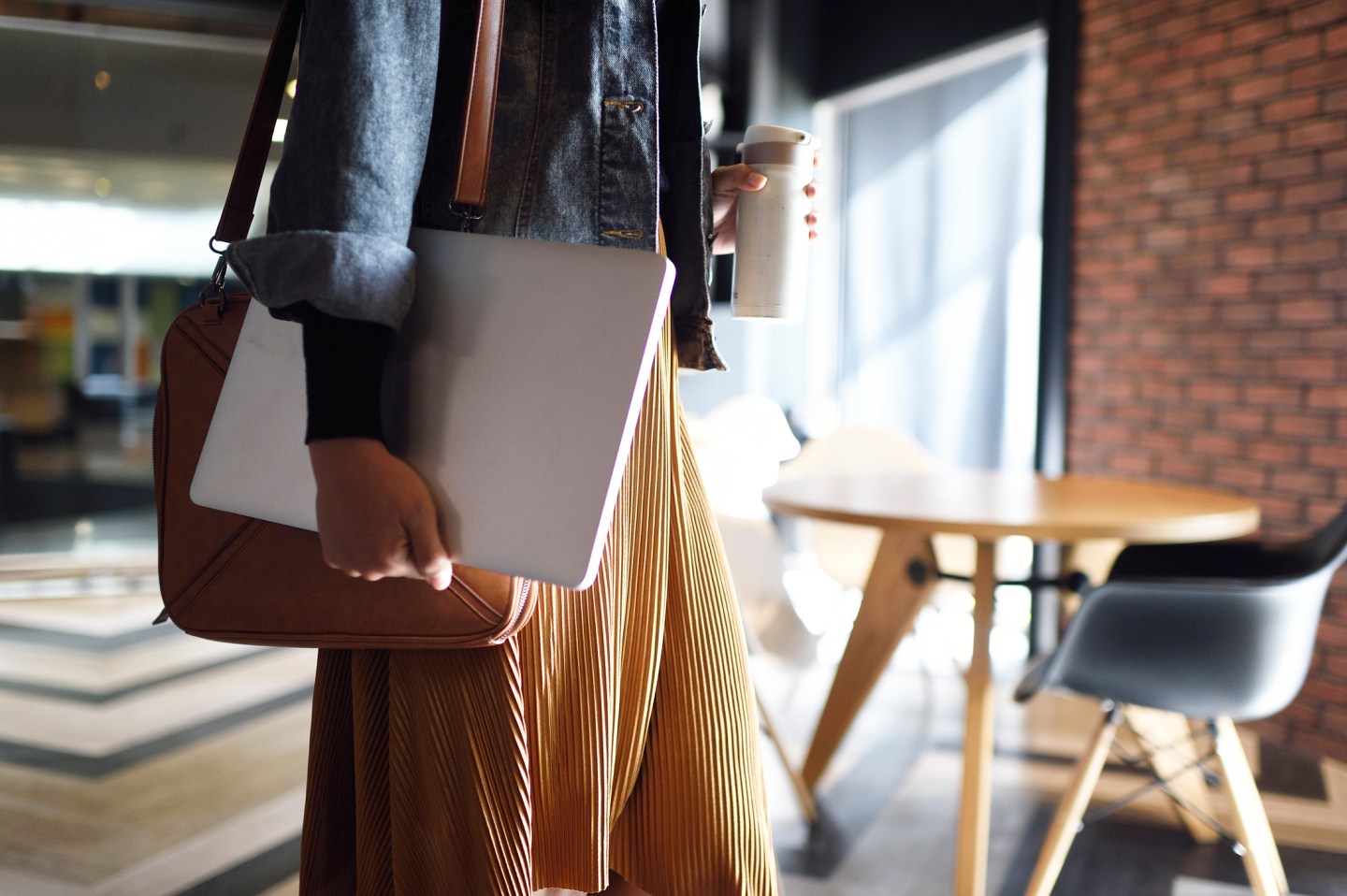 Woman carrying laptop, purse and reusable coffee cup to work