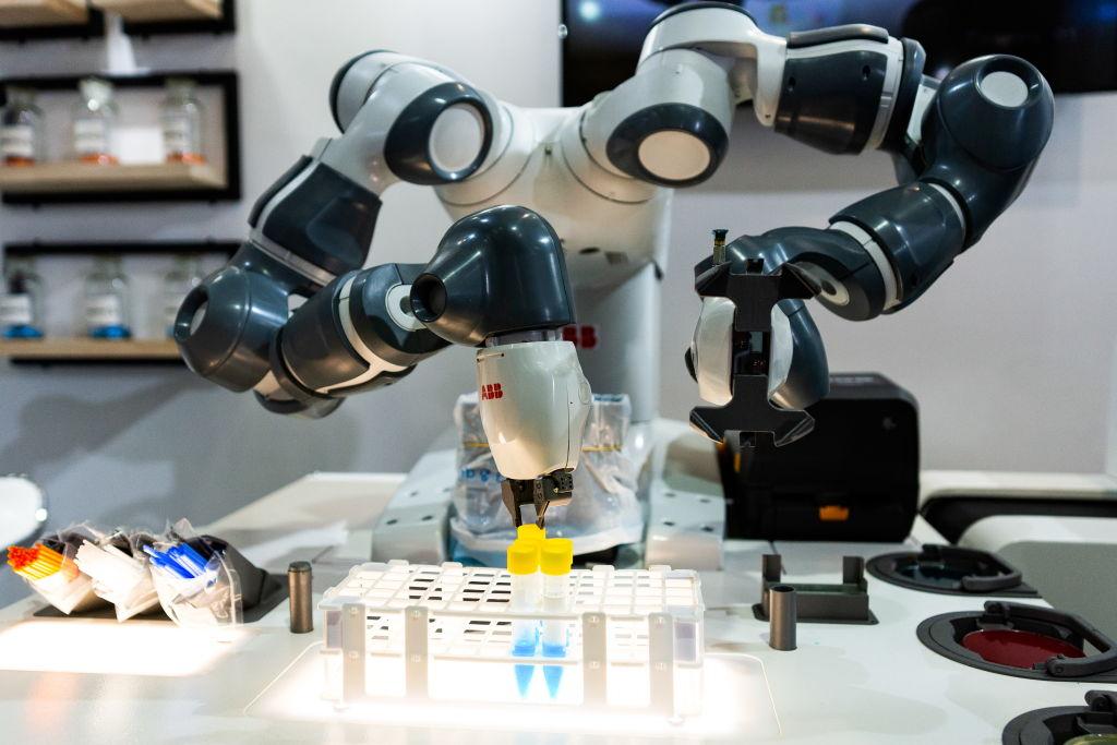 An industrial robot manipulating test tubes of liquid.