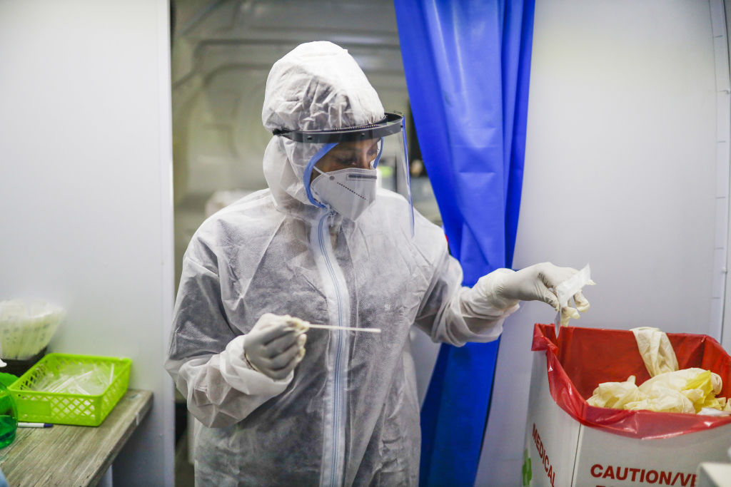 A medical worker in personal protective equipment (PPE) seals a swab sample inside a South Africa Health Department mobile coronavirus testing unit at O.R Tambo International Airport in Johannesburg, South Africa.