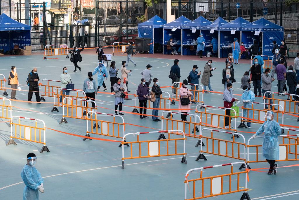 People wearing face masks are seen queuing at a temporary