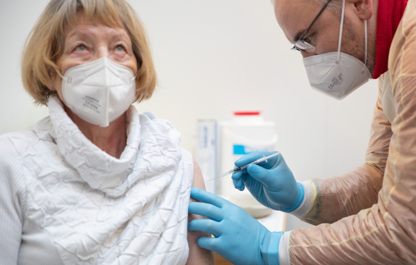 01 February 2021, Lower Saxony, Lingen: Senior citizen Maria Hesemann-Peters is vaccinated against the corona virus with the active ingredient from Biontech/Pfizer by emergency paramedic Bernd Rode from the DRK (German Red Cross) at the vaccination centre in the Emslandhallen.