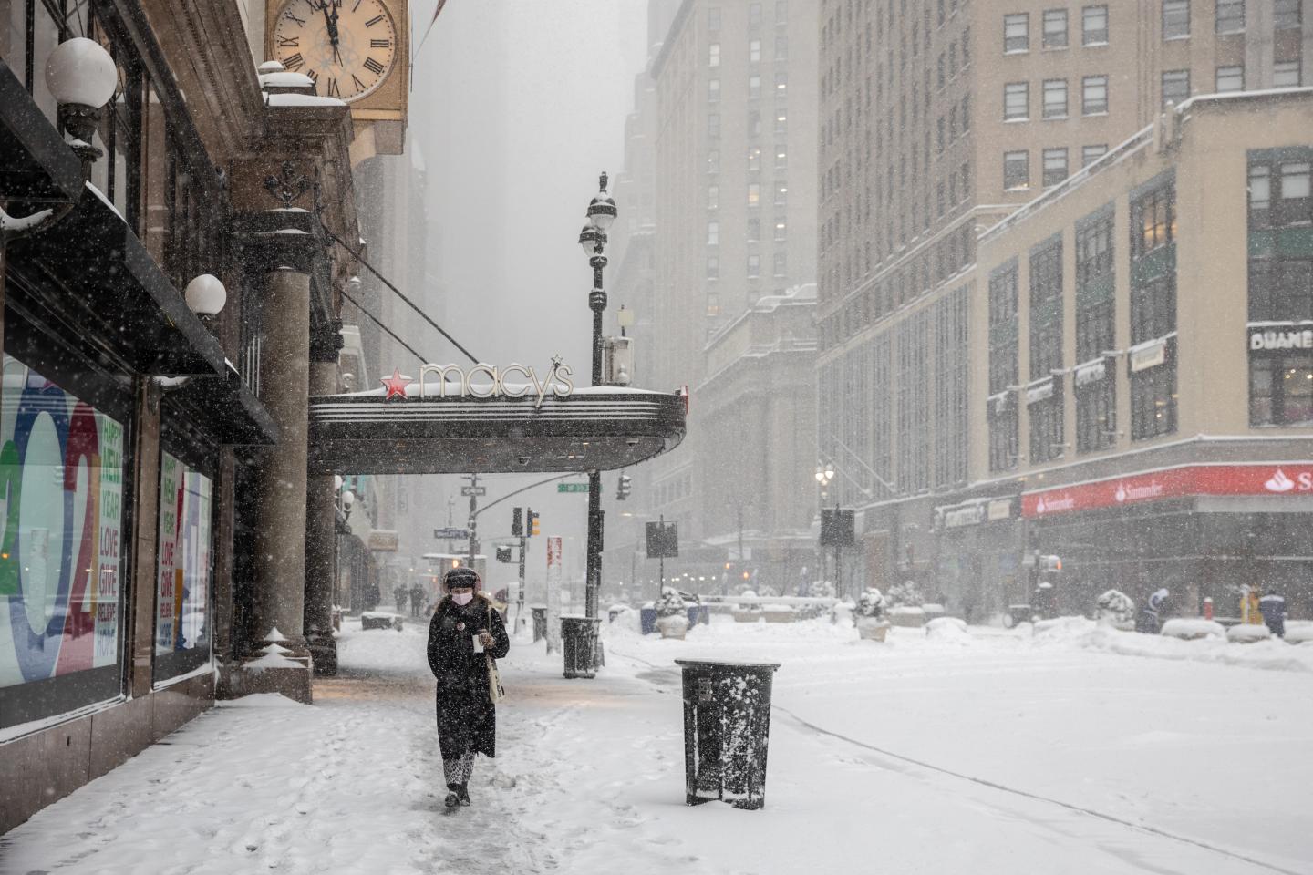 A pedestrian passes in front of Macy's flagship department store as snow falls in the Herald Square area of New York City on Feb. 1, 2021.