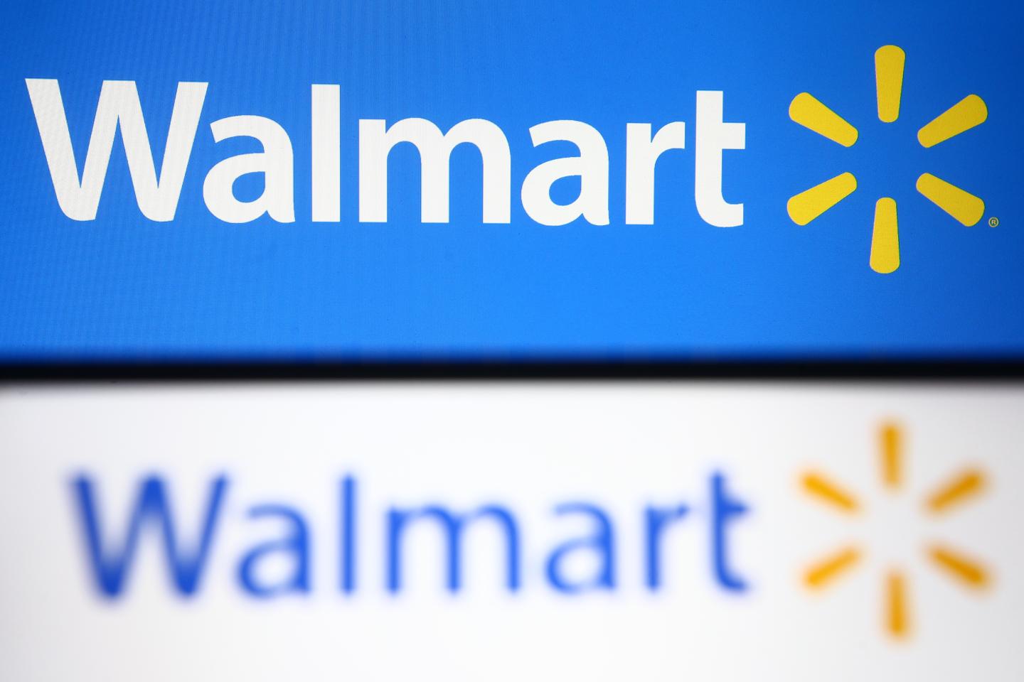 In this photo illustration, Walmart logo is seen displayed on a smartphone and a pc screen.