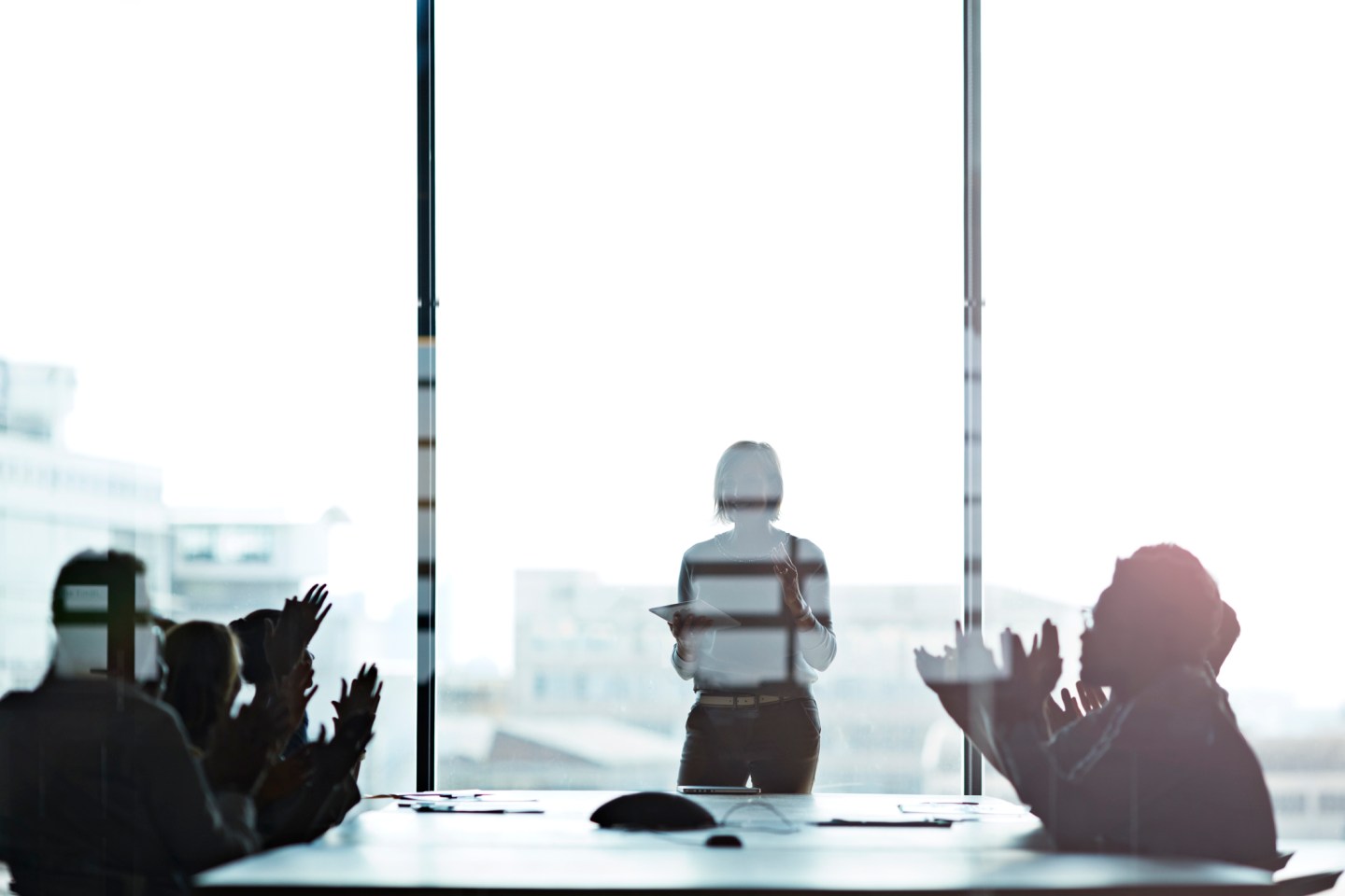 Businesswoman presenting, co-workers clapping