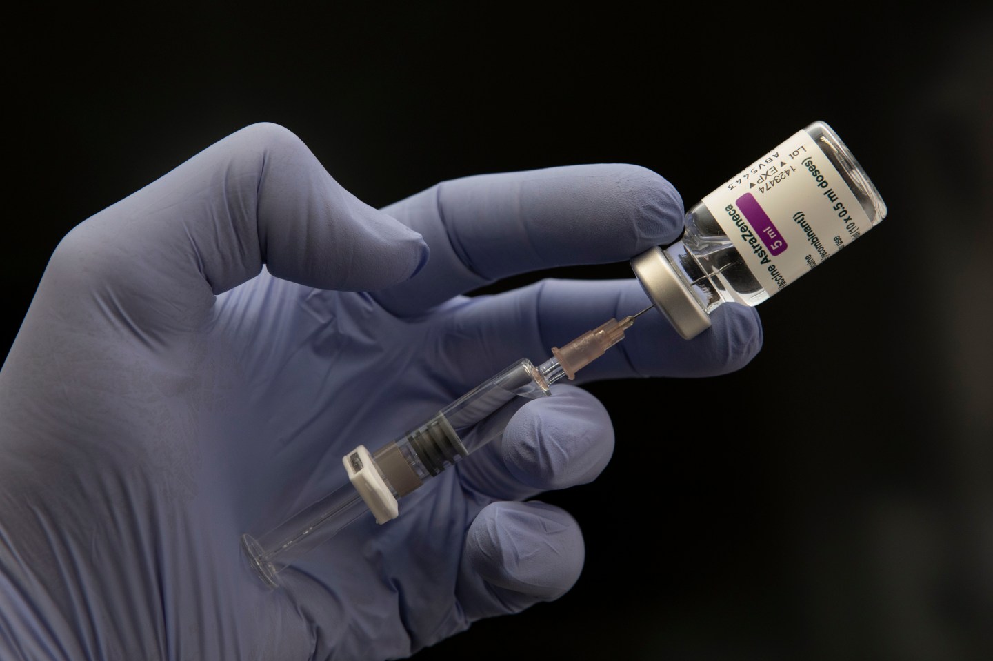 Photo of gloved hand holding syringe and vial of Astrazeneca vaccine