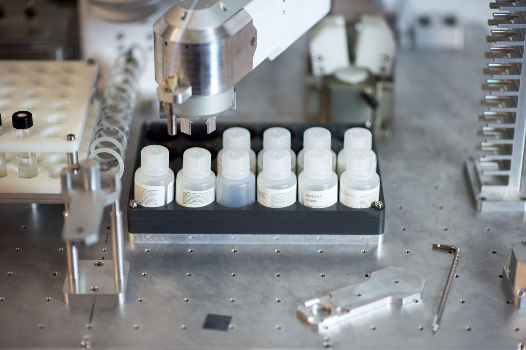 A robot arm moving vials in a drug research lab.