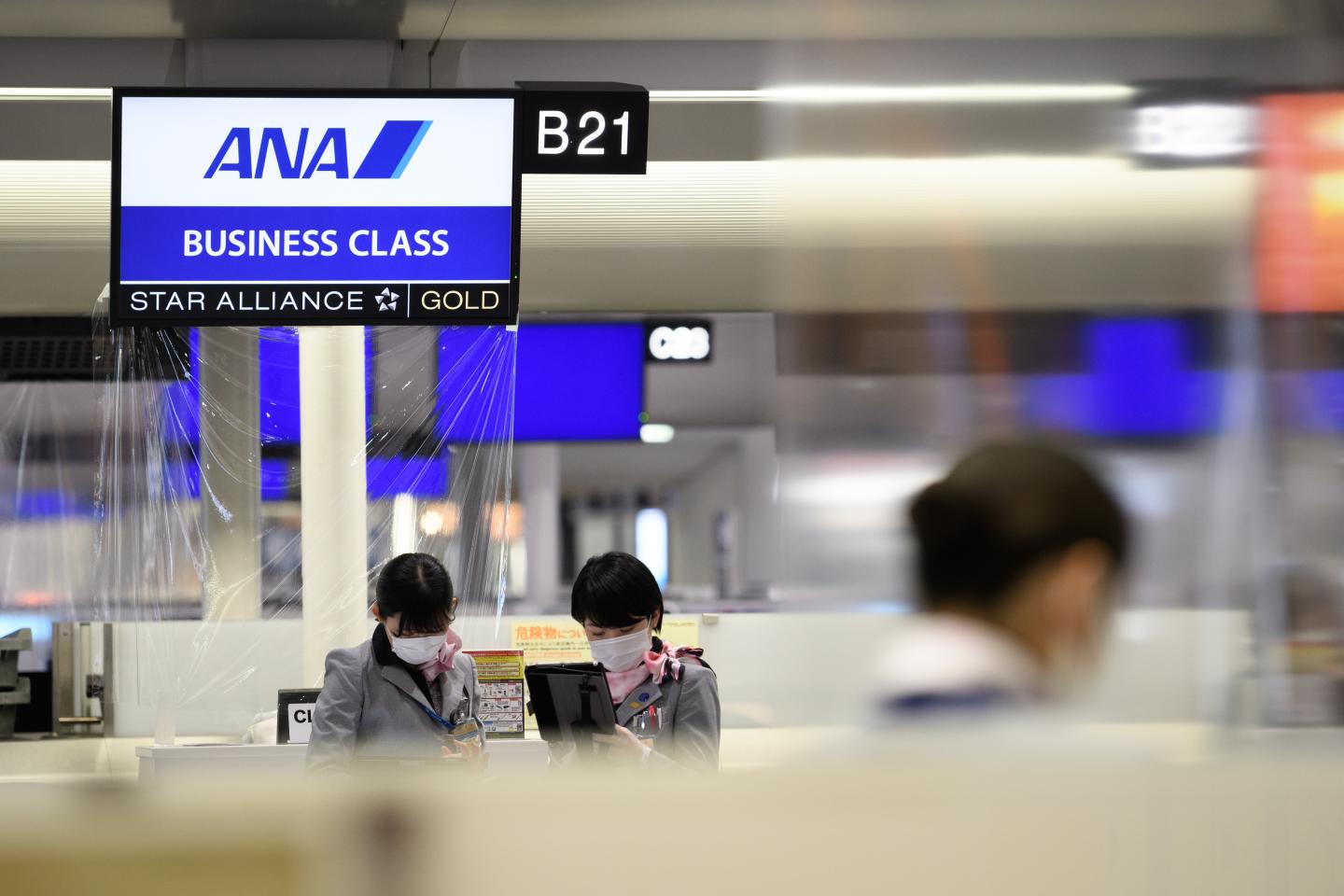 Employees wearing protective masks work at the All Nippon Airways Co. (ANA) check-in desk inside Narita Airport in Narita, Chiba Prefecture, Japan, on Friday, Feb. 12, 2021.