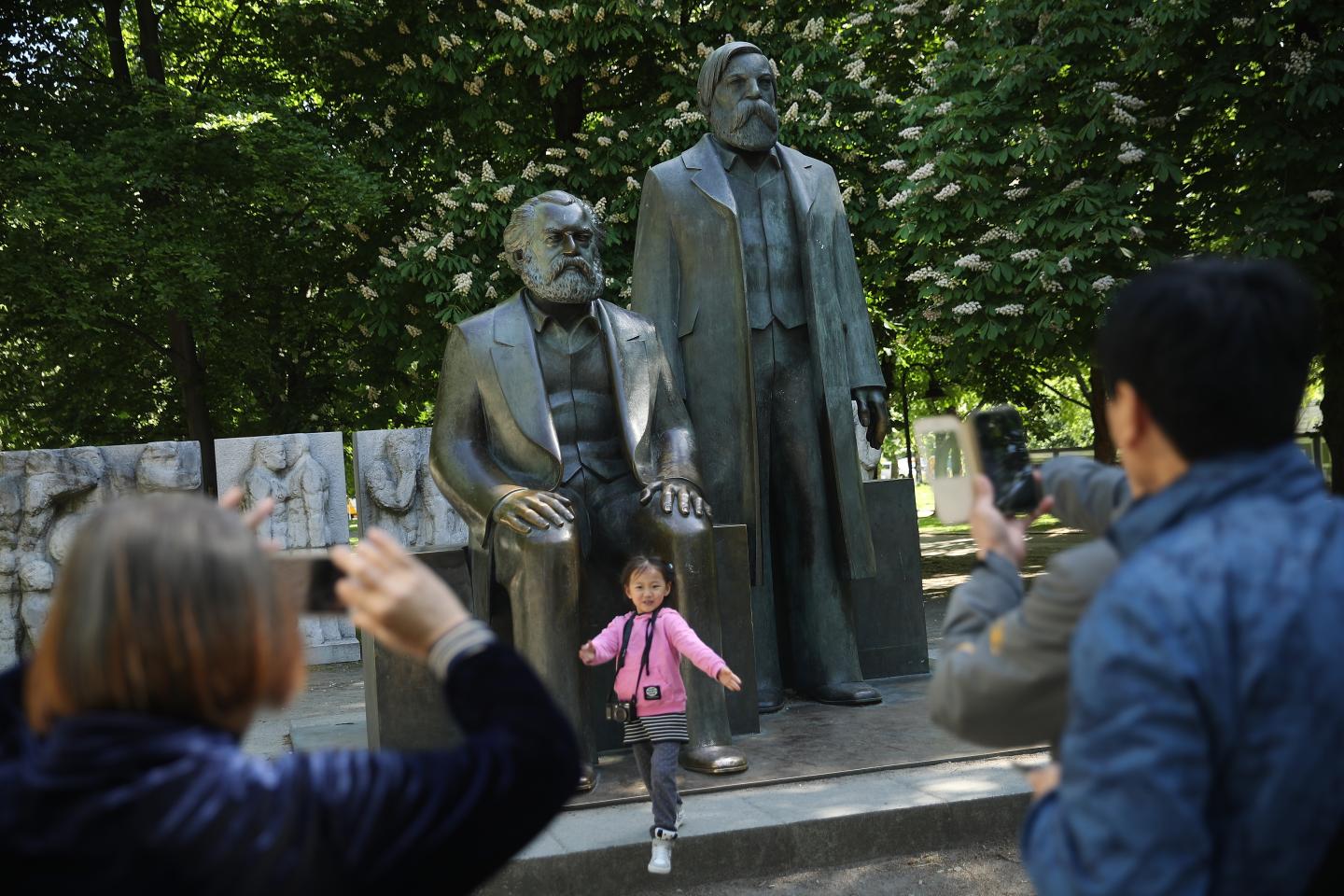 Visitors from China photograph one another in front of a statue of philosopher and revolutionary Karl Marx on May 4, 2018 in Berlin, Germany.