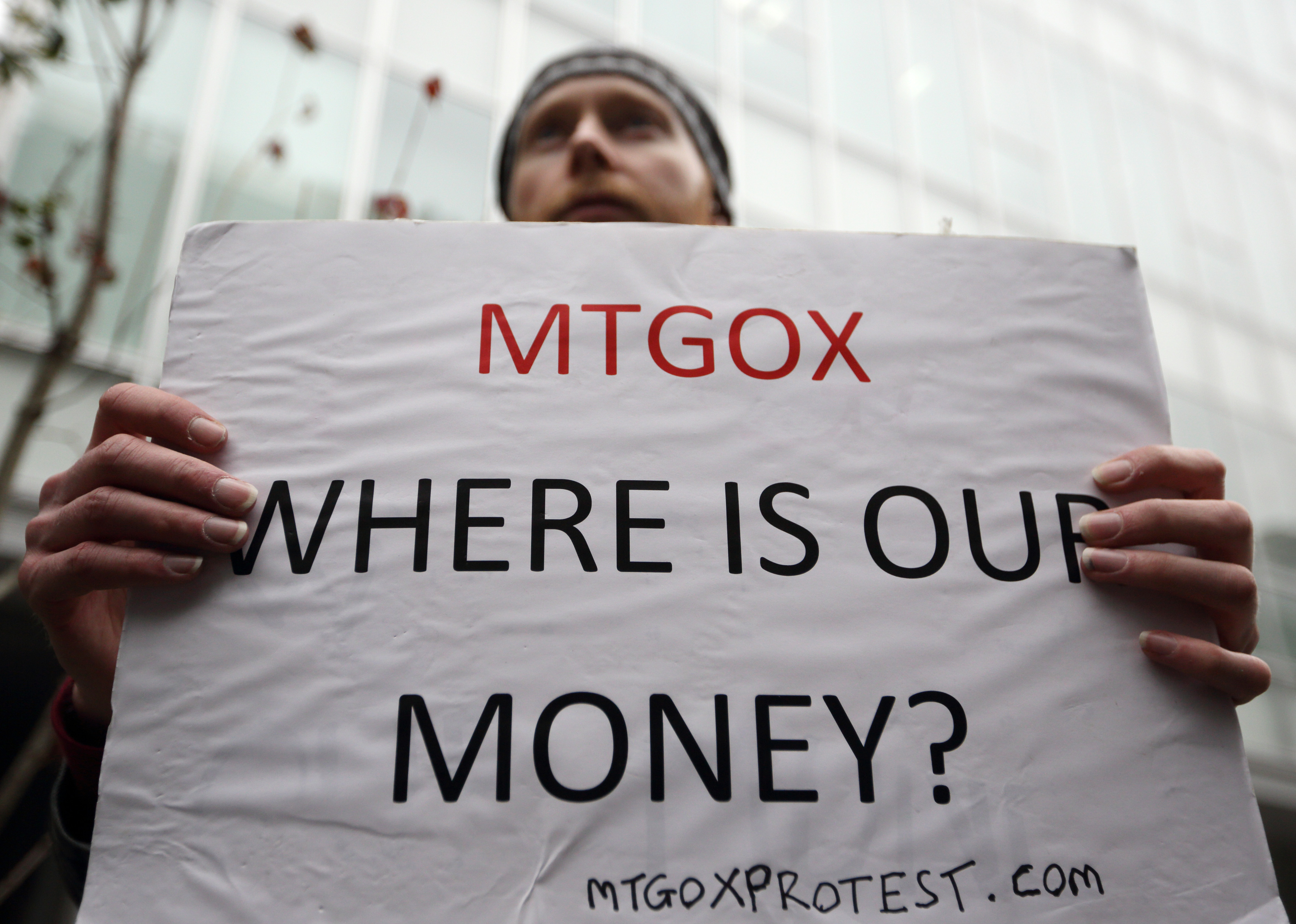 A customer holds a placard in front of the Mt. Gox Bitcoin exchange in Tokyo, on Feb. 27, 2014.