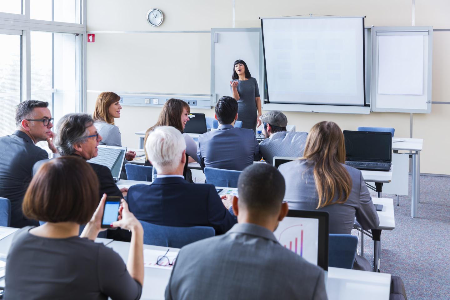Business people listen to a classroom lecture.