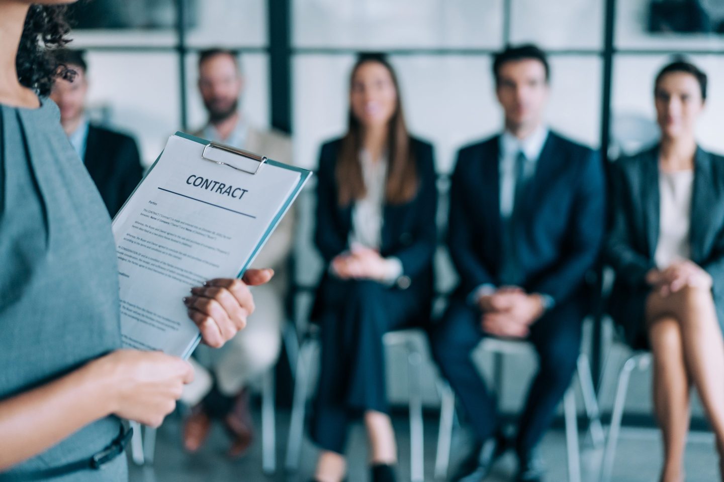 A group of business people sit in line waiting for a job interview.