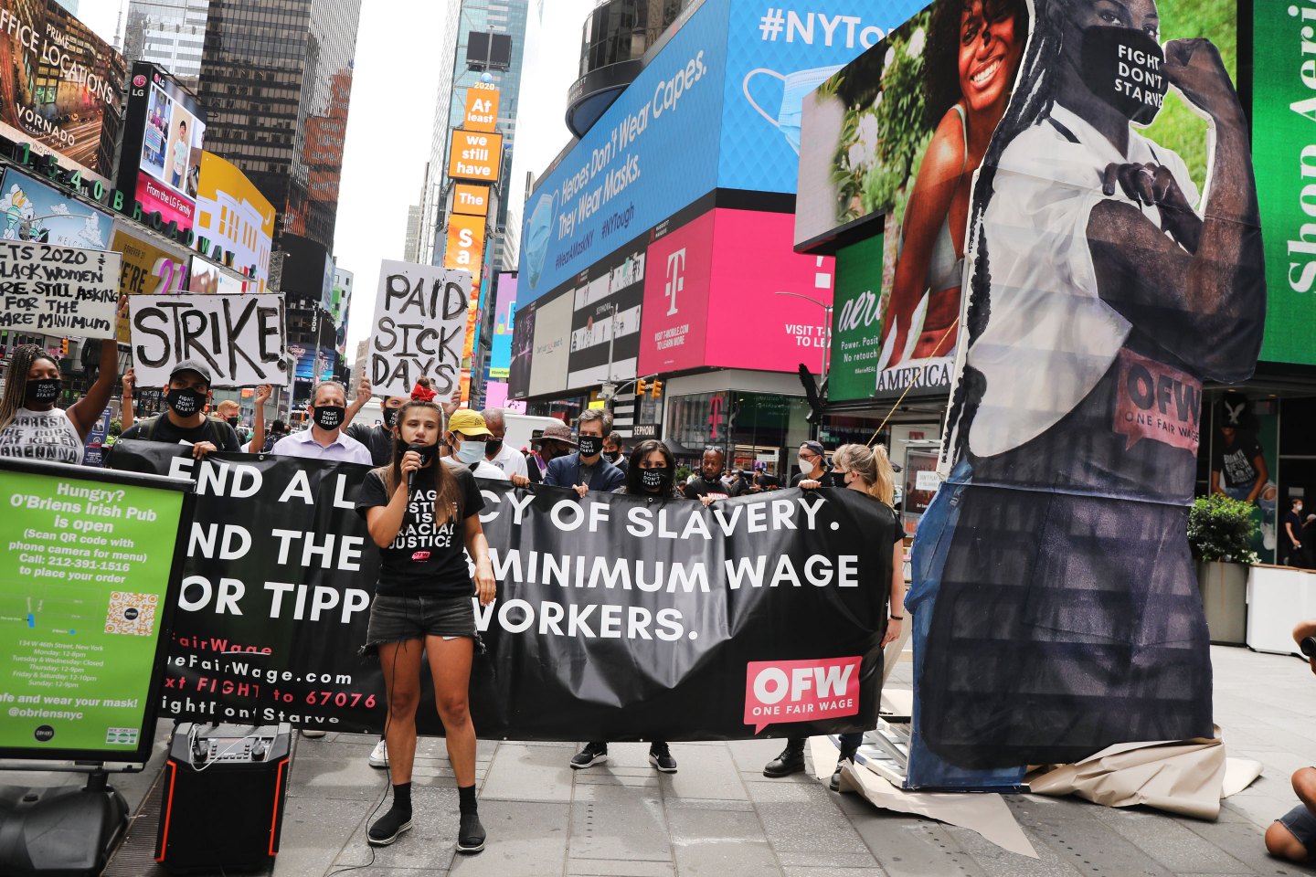 NEW YORK, NEW YORK &#8211; AUGUST 31: With a a 24-foot wooden statue of &#8216;Elena the Essential Worker&#8217; next to them, activists from One Fair Wage hold a demonstration in Times Square to demand a &#8216;fair wage&#8217; for tipped workers during coronavirus and beyond on August 31, 2020 in New York City. Demanding that all employers pay the full minimum wage with fair, non-discriminatory tips on top, the One Fair Wage campaign seeks to lift millions of tipped and sub minimum wage workers nationally out of poverty. According to the group, the restaurant industry includes 7 of the 10 lowest paying jobs in the country. (Photo by Spencer Platt/Getty Images)