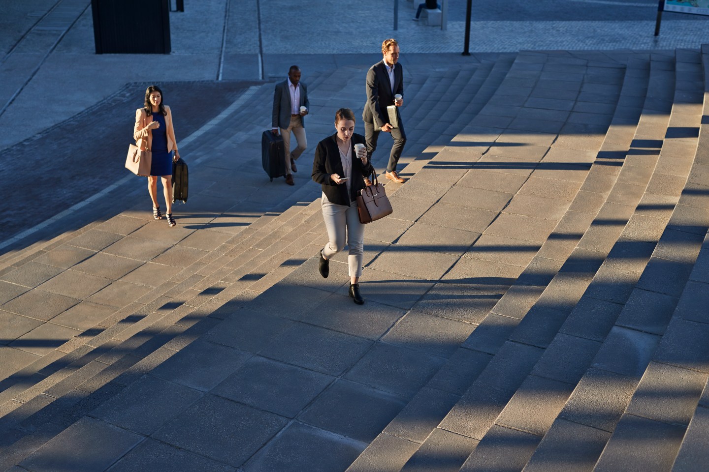 Businesspeople walking with bags on staircase outside, at sunrise