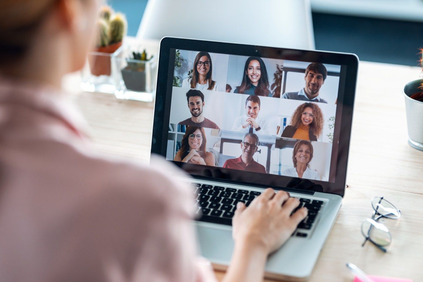 Back view of female employee speaking on video call with diverse colleagues on online briefing with laptop at home.