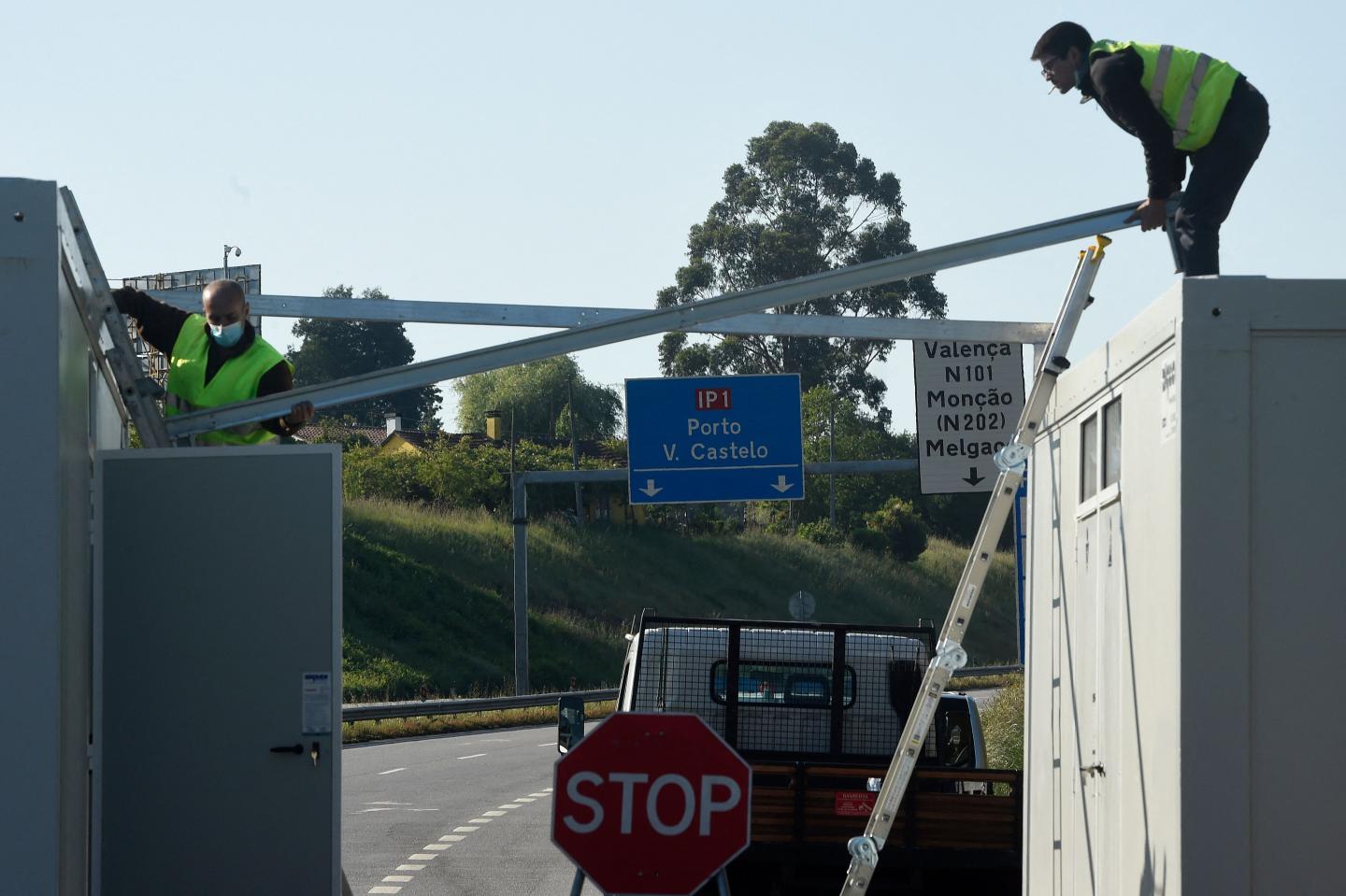 Workers dismantle a checkpoint along the Portuguese-Spanish land border crossing between Valenca and Tui on May 1, 2021 following its reopening as Portugal eased coronavirus restrictions.