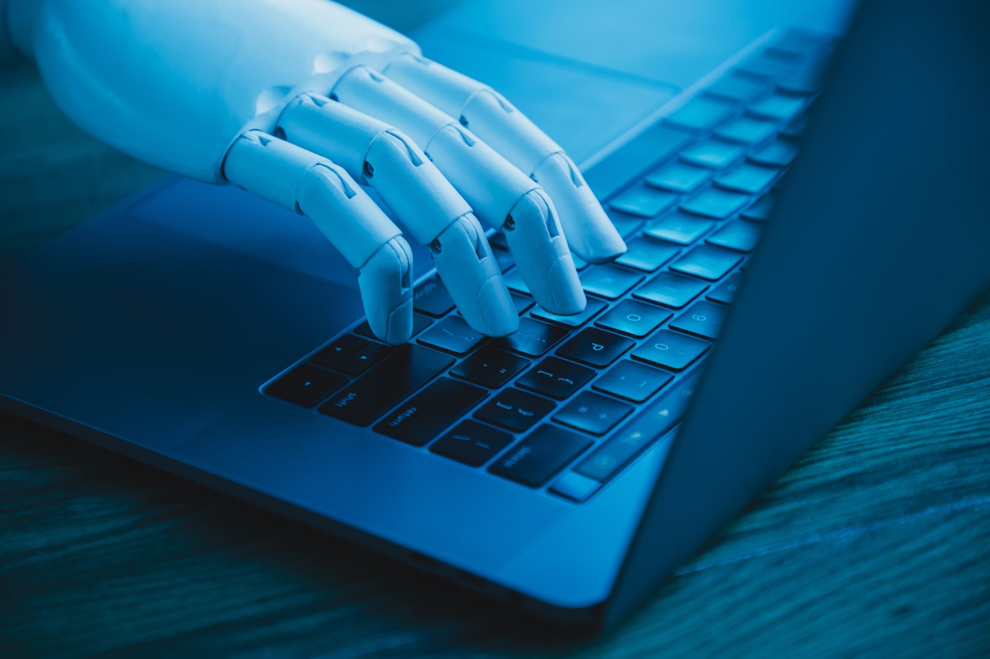 robotic hand using laptop (concept of AI replacing white collar worker)