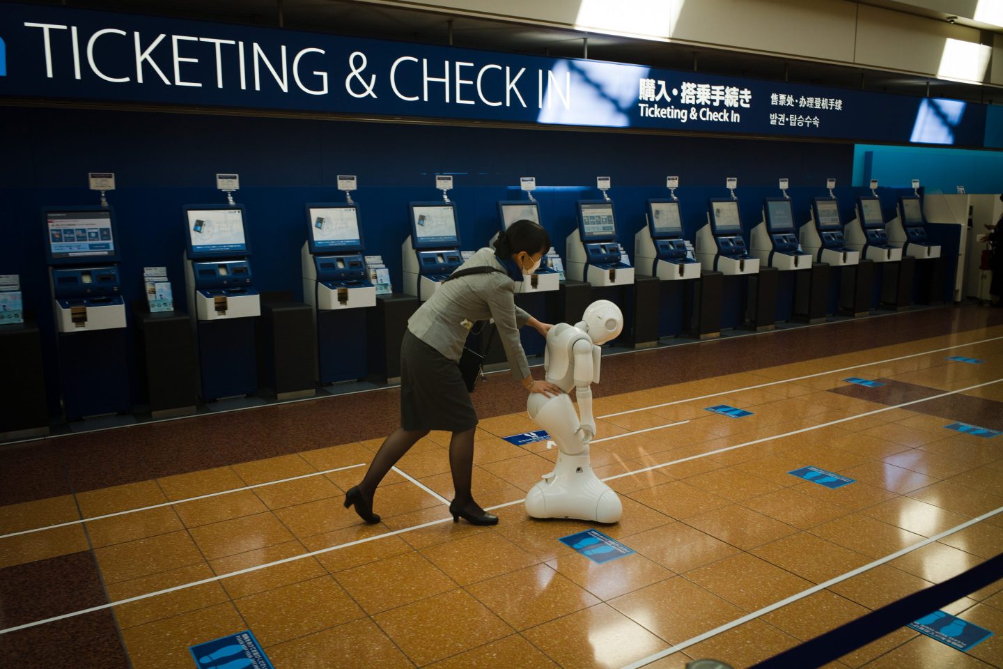 A member of All Nippon Airways Co. (ANA) ground crew moves a SoftBank Group Corp. Pepper humanoid robot at Haneda Airport departures lobby on Sunday, Oct. 25, 2020.