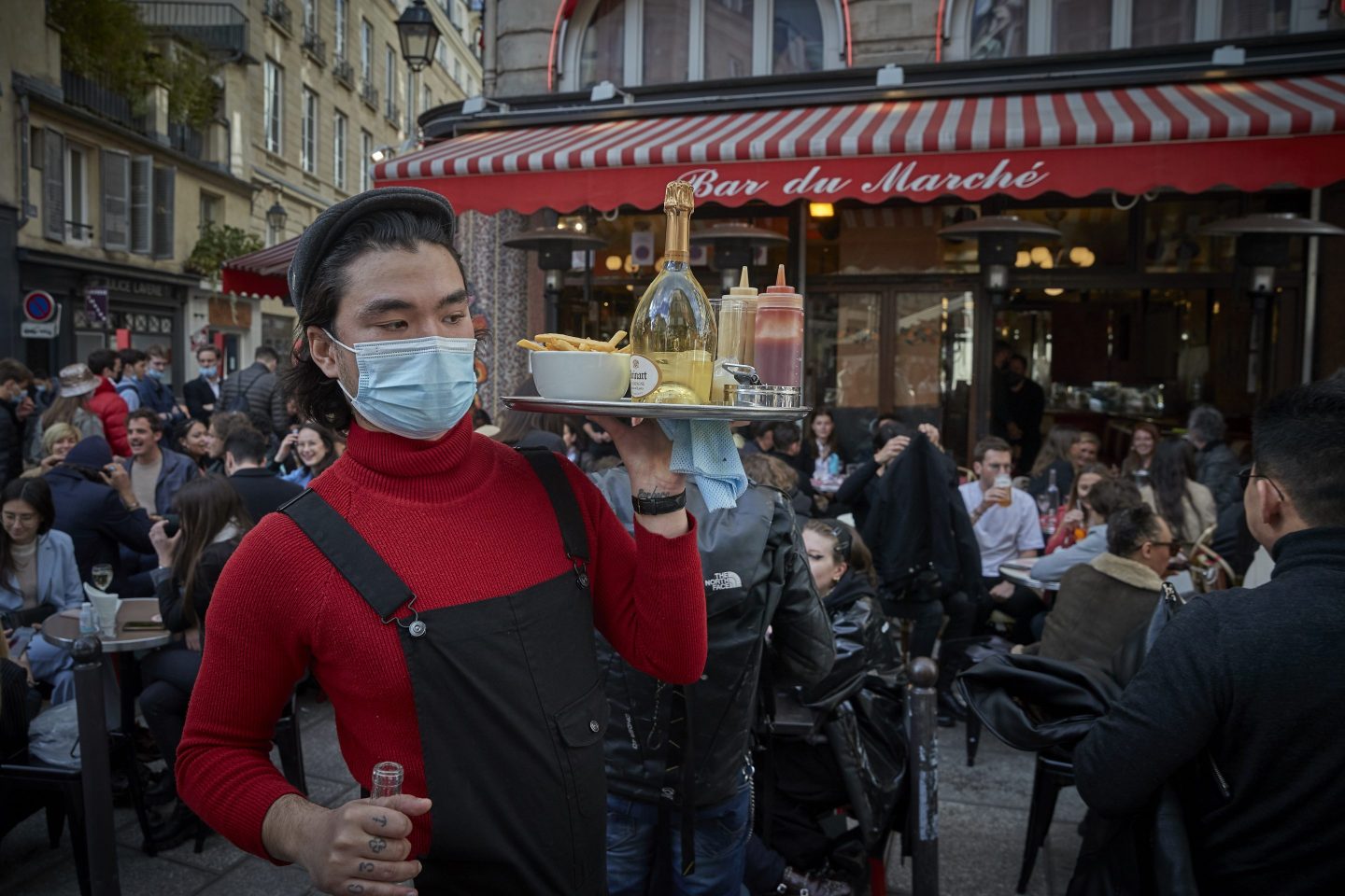 PARIS, FRANCE - MAY 19: A waiter serves customers on the terrace at Bar du Marche in Paris' 6th Arrondissement as cafes and restaurants across France re-open for the first time in over 6 months on May 19, 2021 in Paris, France. France is taking steps to ease the lockdown measures allowing cafe and restaurant terraces to open to 50% capacity, rolling back the nightly curfew to 9pm and reopening non-essential shops and cultural venues. France is currently reporting a seven-day average of around 14,000 new Covid-19 cases.