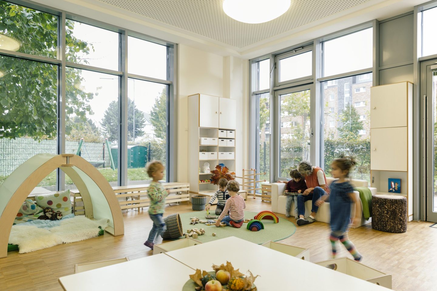Pre-school teacher and children in playing in learning room in kindergarten