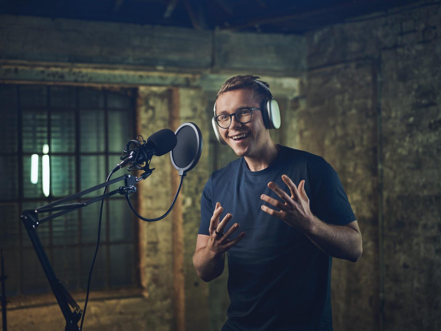 Photo of Harry Stebbings at a microphone recording a podcast.