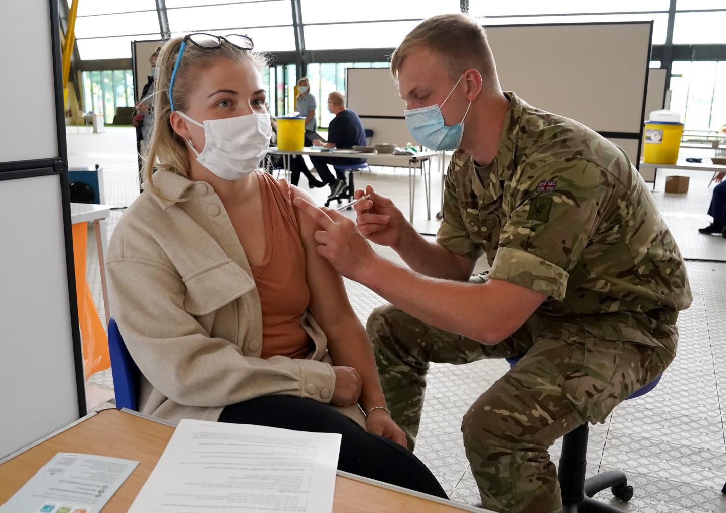 A British soldier giving a woman a coronavirus vaccine injection.