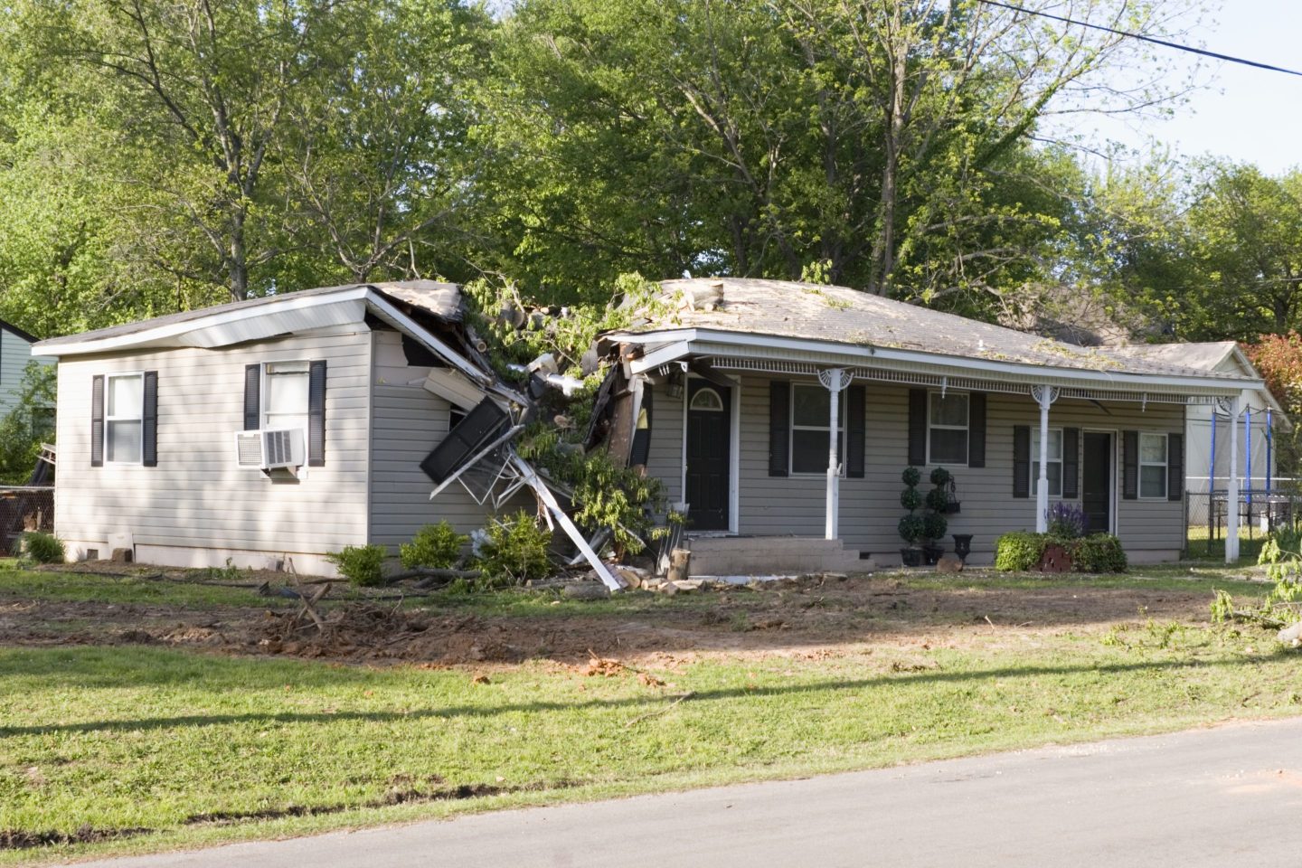 Image of a house half caved in after a tree fell through its roof.