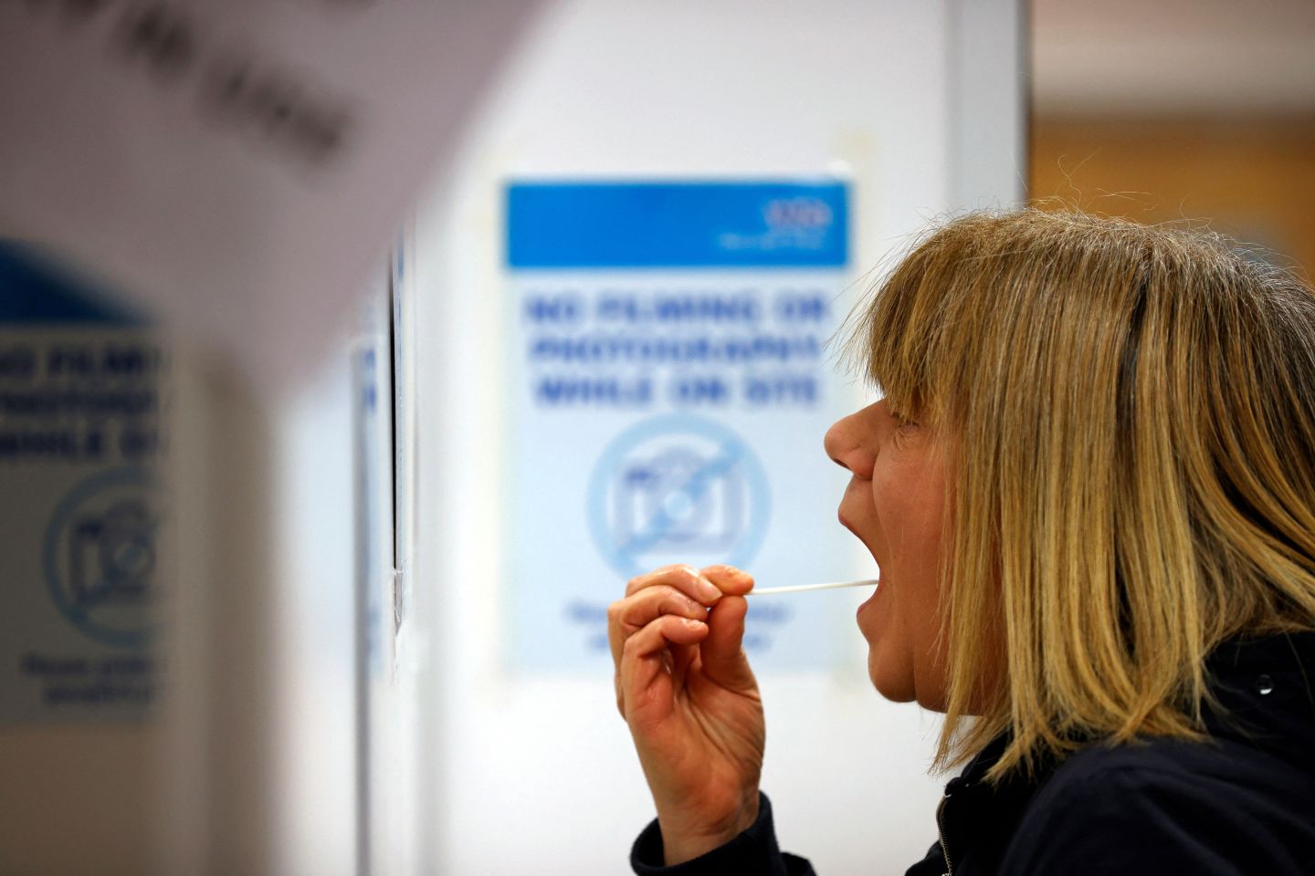 A woman uses a swab to take a sample from her mouth at a NHS Test and Trace Covid-19 testing unit at the Civic Centre in Uxbridge, Hillingdon, west London on May 25, 2021, as "surge testing" takes place in several areas of the country in order to keep on top of new Covid variants.