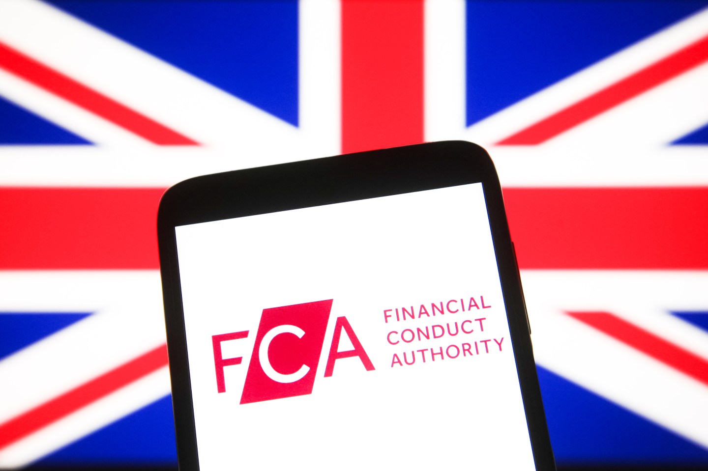 In this photo illustration, Financial Conduct Authority (FCA) logo is seen on a smartphone screen with British flag in the background.