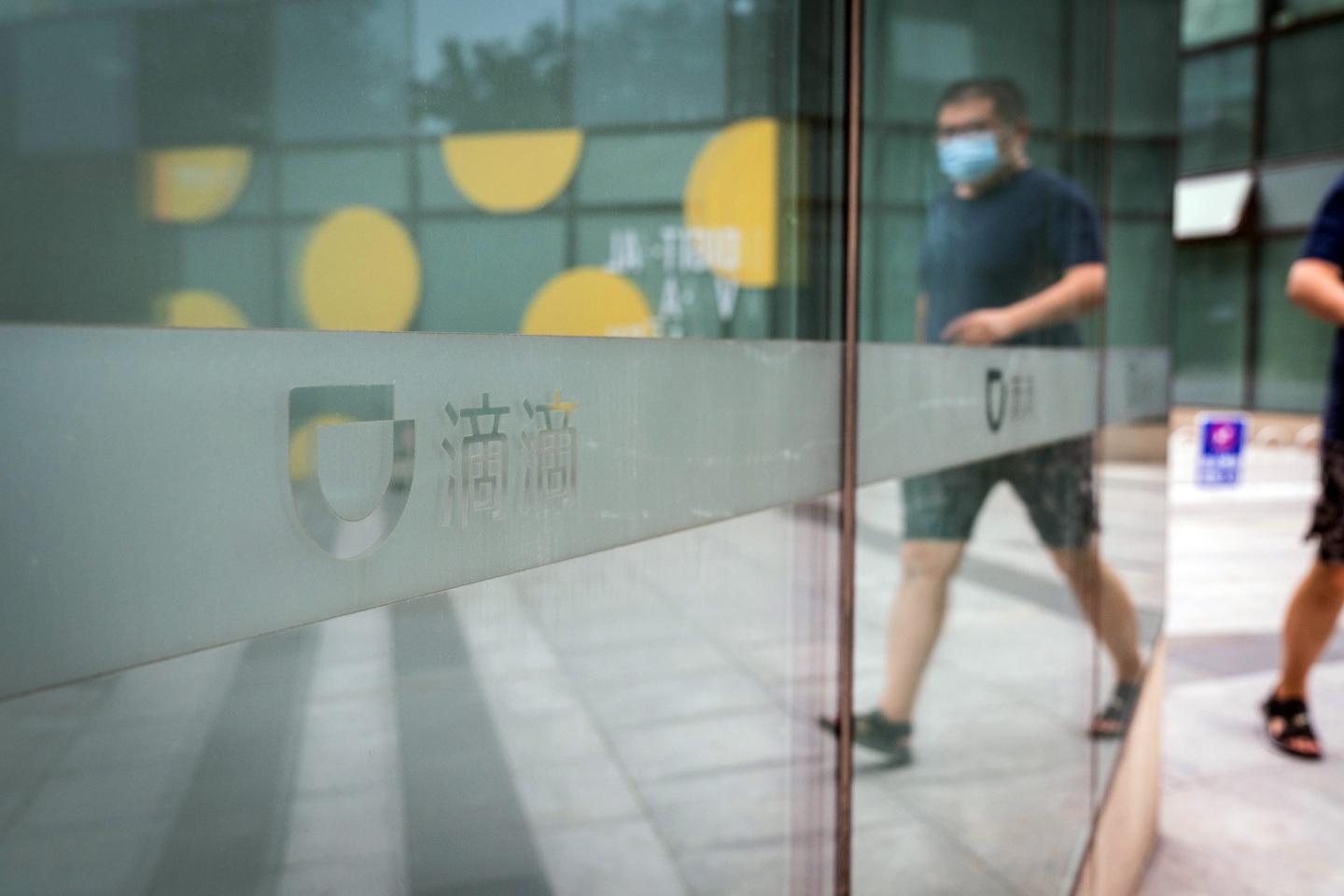 A pedestrian pass a logo at the Didi Global Inc. headquarters in Beijing, China, on Monday, July 5, 2021. China expanded its latest crackdown on the technology industry beyond Didi to include two other companies that recently listed in New York, dealing a blow to global investors while tightening the governments grip on sensitive online data. Photographer: Yan Cong/Bloomberg via Getty Images