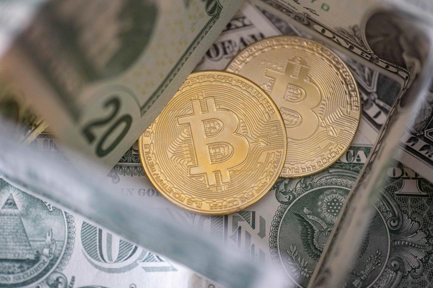 Bitcoin golden physical coin illustration on United States Dollar banknotes.