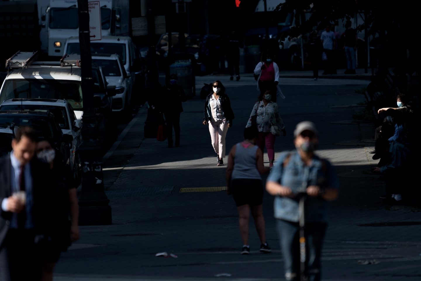 A woman wearing a mask walks through a patch of sunlight in Lower Manhattan on May 25, 2021 in New York City.