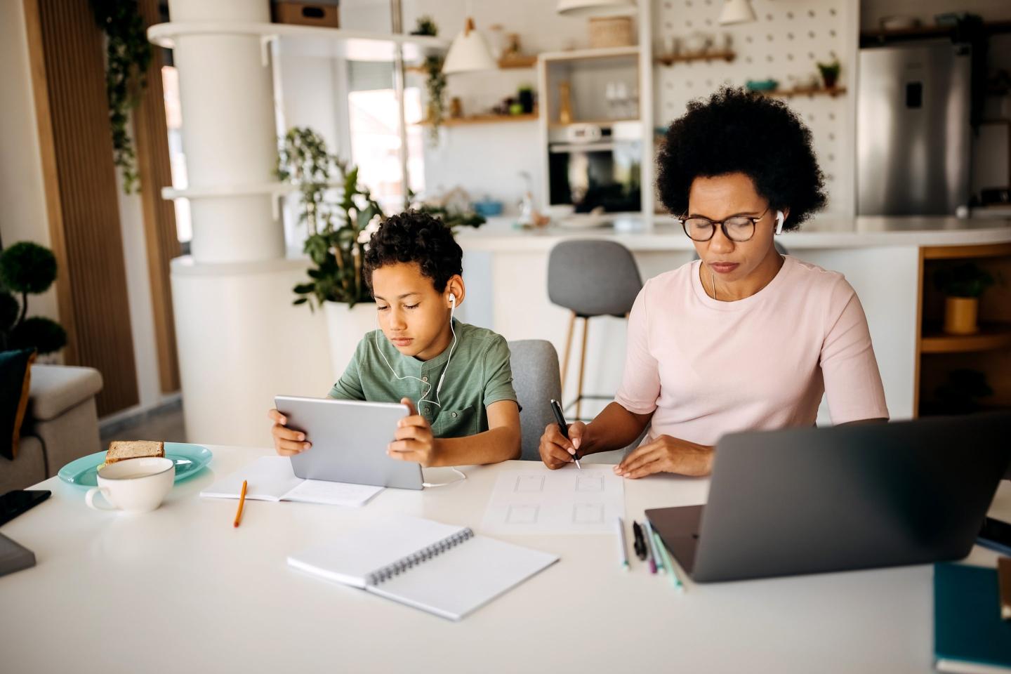 woman working on laptop with child sitting next to her.