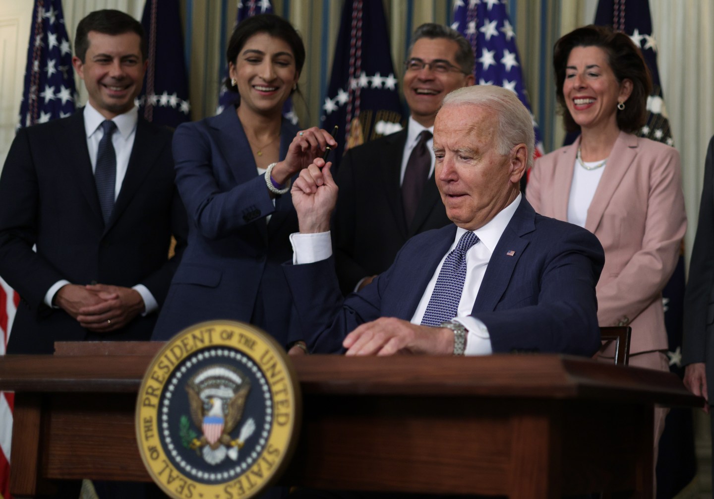 U.S. President Joe Biden passes a signing pen to Chairperson of the Federal Trade Commission Lina Khan (2nd L) as (L-R) Secretary of Transportation Pete Buttigieg, Secretary of Health and Human Services Xavier Becerra, and Secretary of Commerce Gina Raimondo look on during an event at the State Dining Room of the White House July 9, 2021 in Washington, DC. President Biden signed an executive order on “promoting competition in the American economy.”