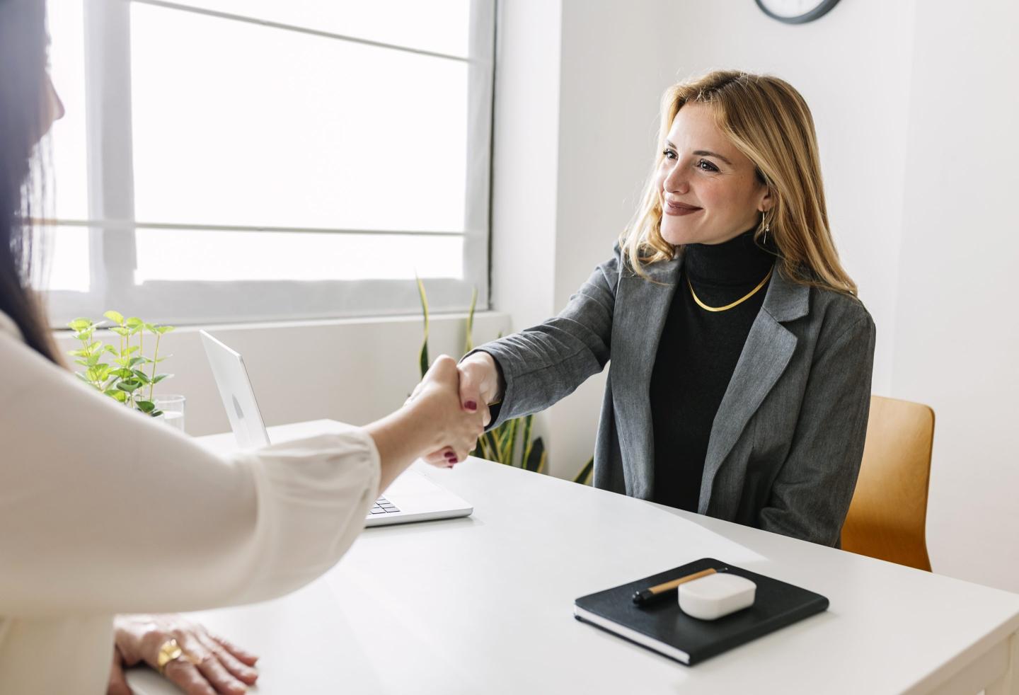 Woman smiles as she shakes hands with a candidate.