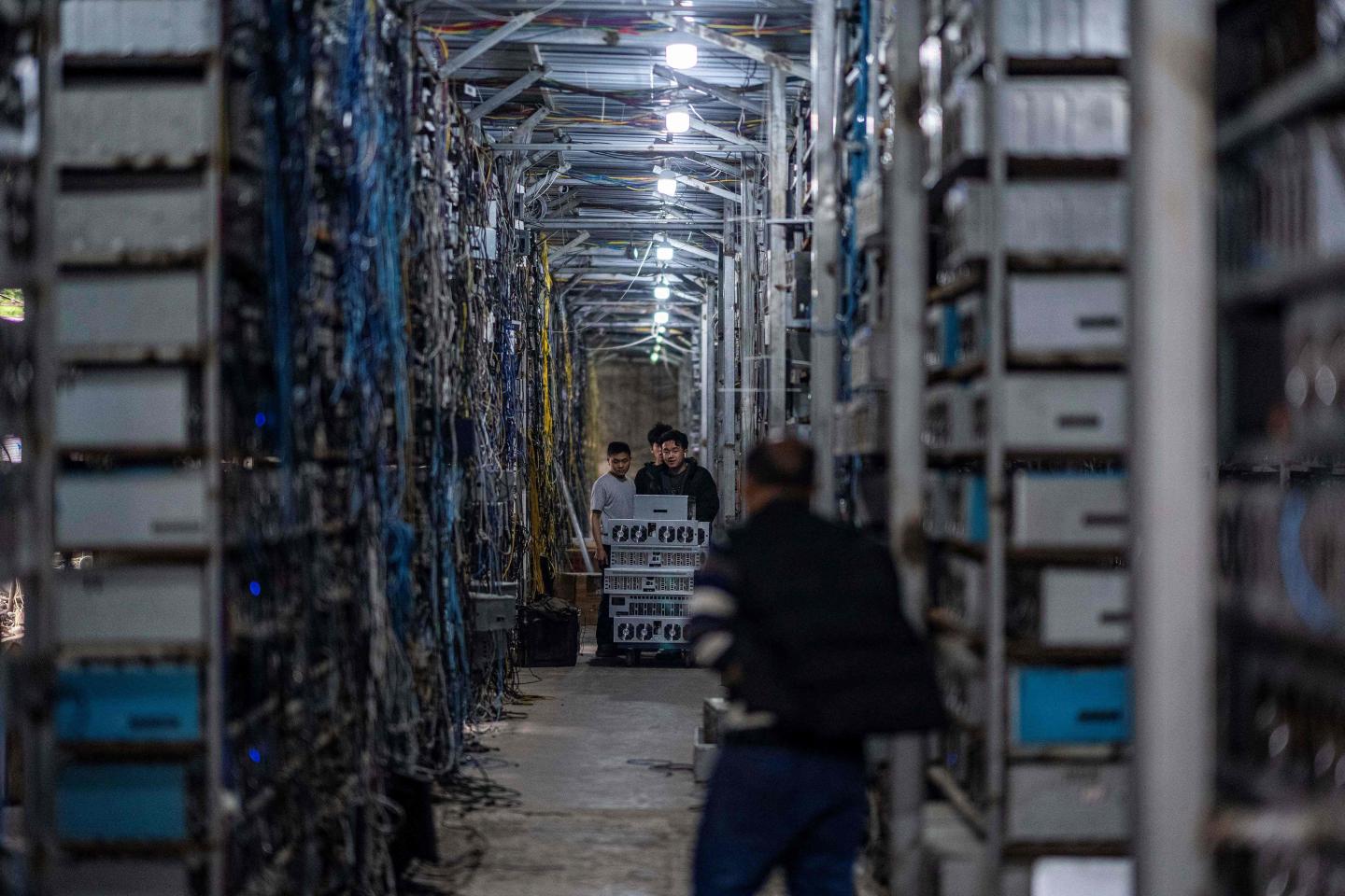 workers transferring cryptocurrency mining rigs at a cryptocurrency farm