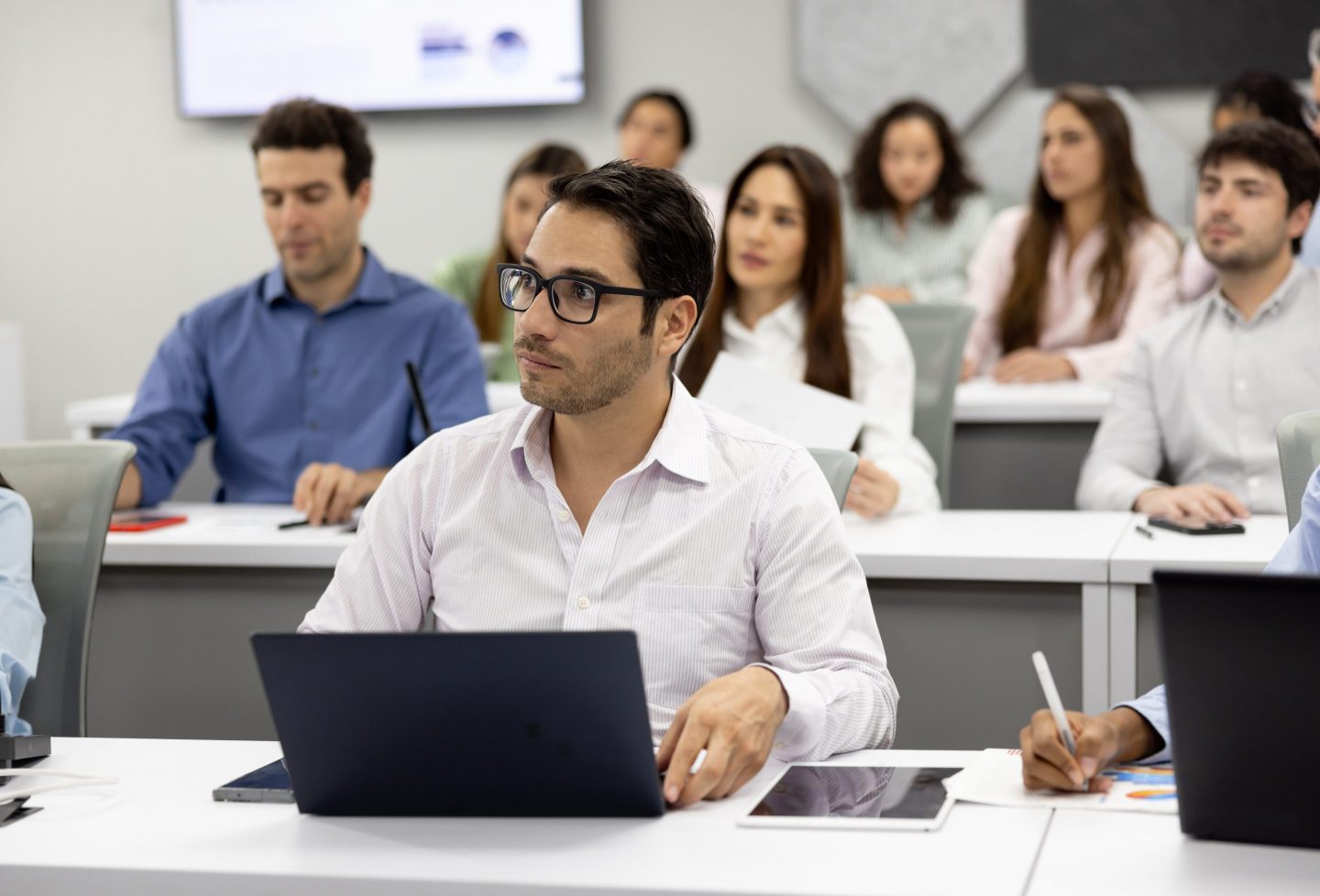 Man using a laptop in a business school classroom.