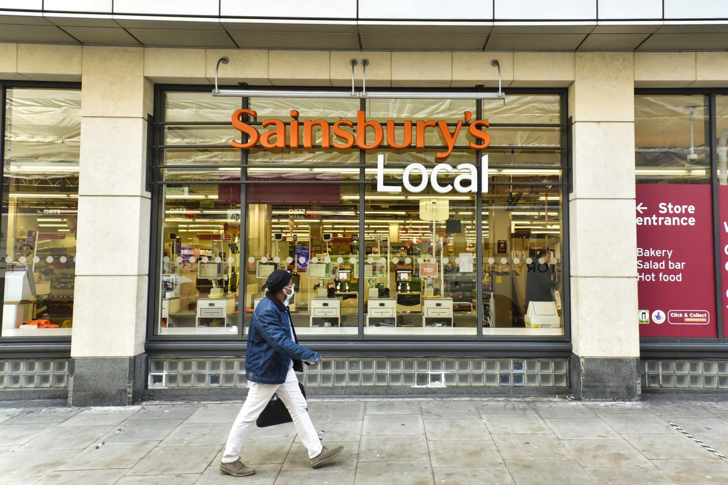 A man wearing a face mask walks past the Sainsburys shop