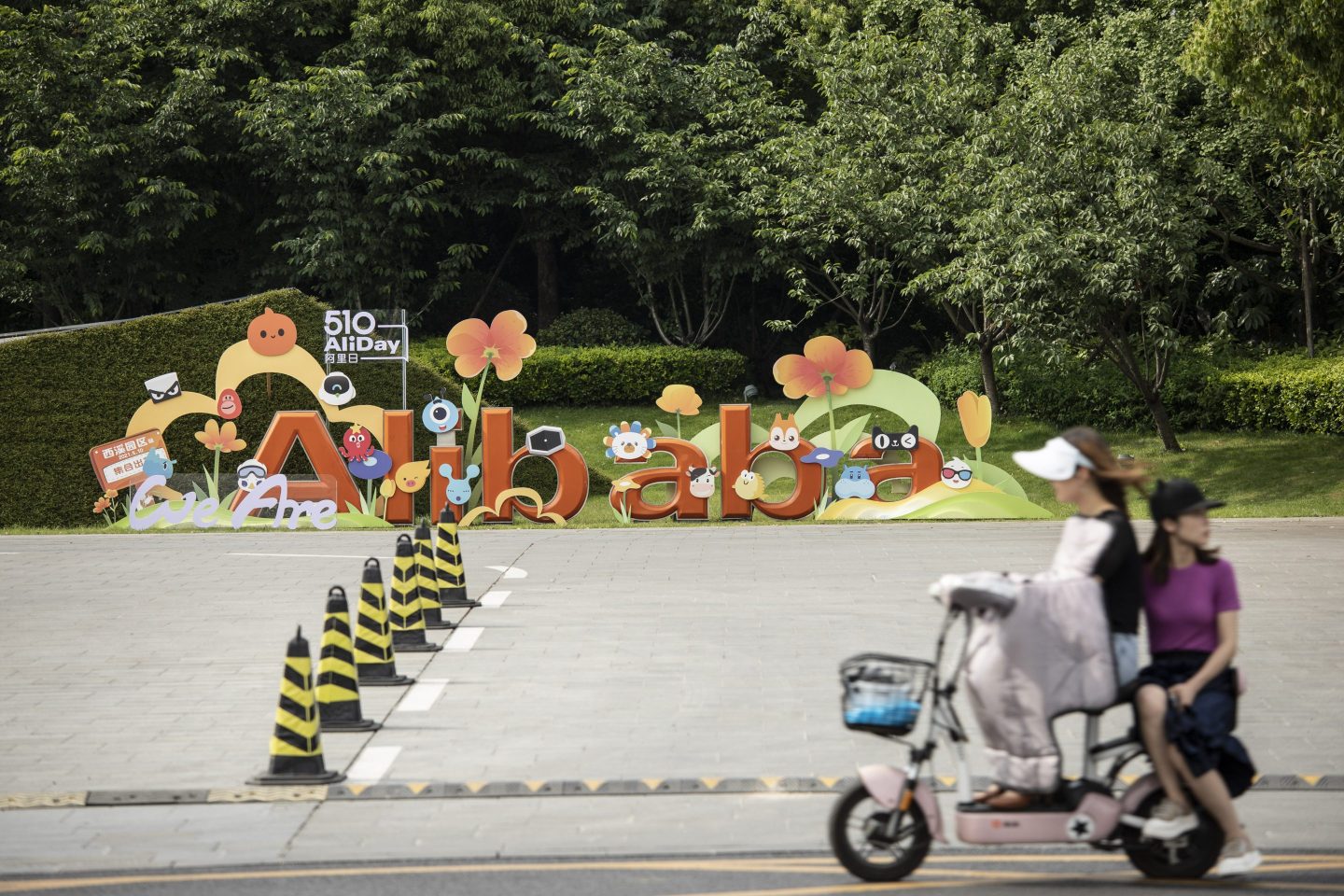 Women ride past a sign at Alibaba Group Holding headquarters in Hangzhou in May 2021.