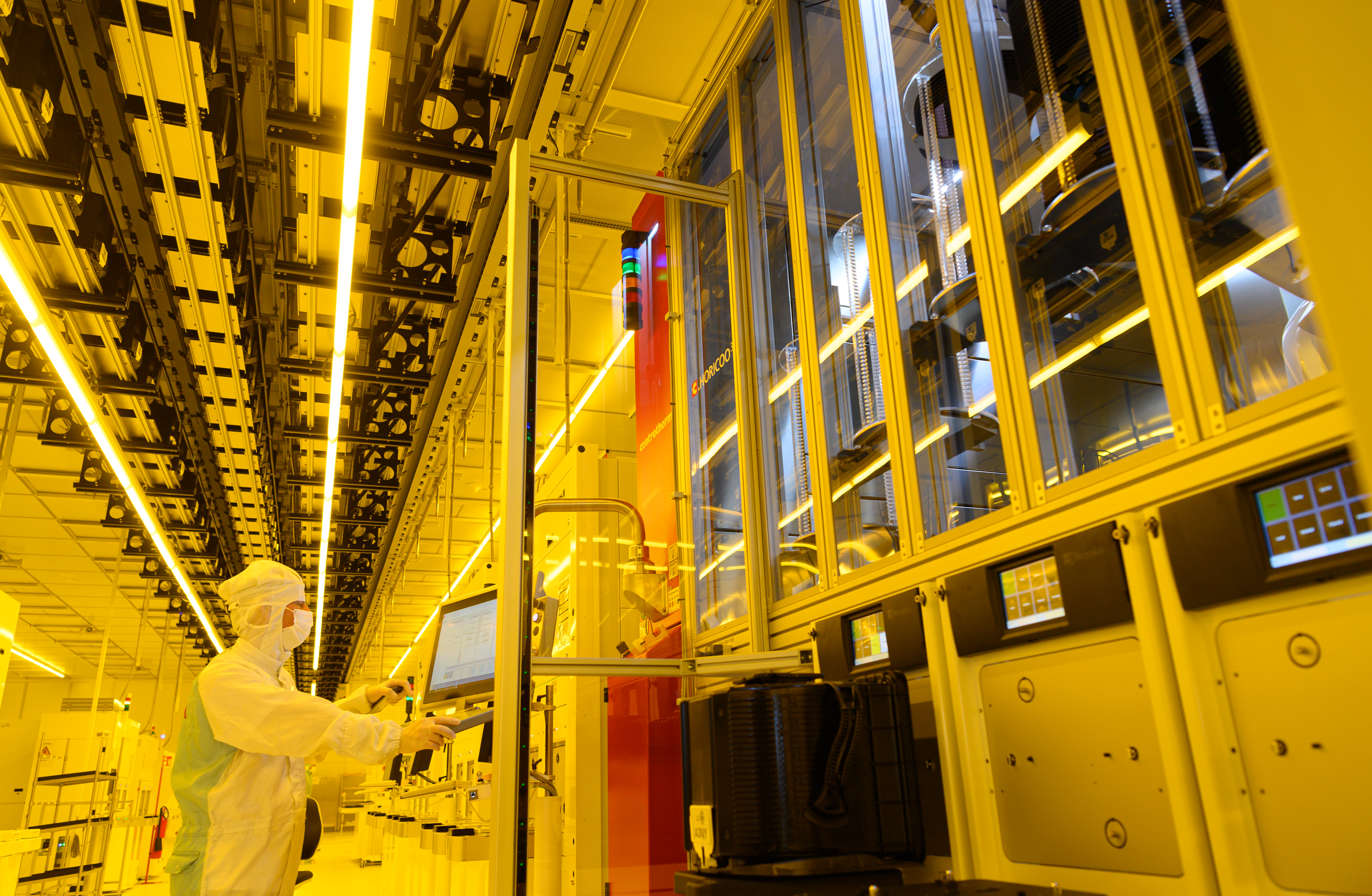 During a press tour of Bosch's new semiconductor factory, an associate stands in the clean room at a machine for mounting 300-millimeter wafers.