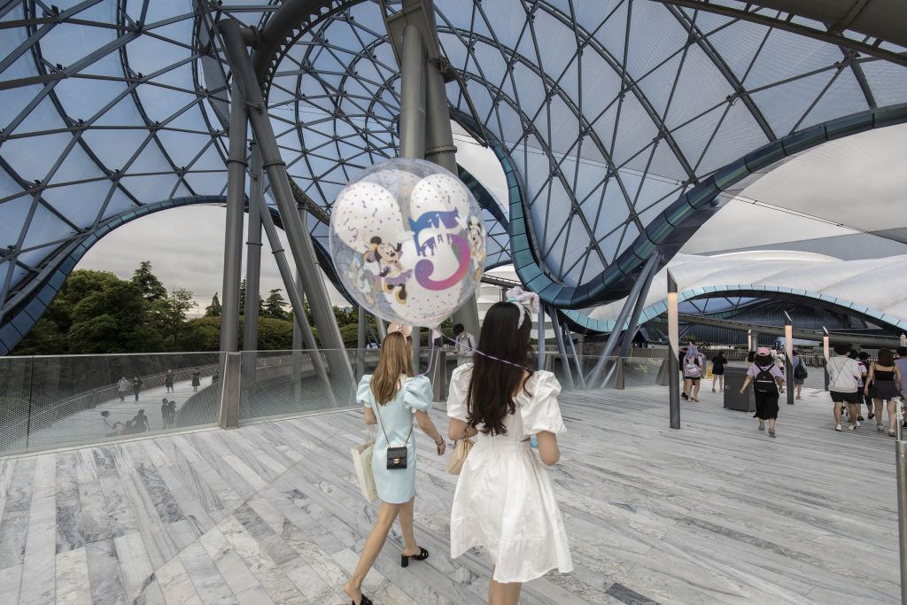 A visitor carries a balloon marking the fifth anniversary of the Walt Disney Co. Shanghai Disneyland theme park on June 16, 2021. 